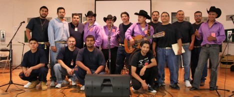 Members of the Latino Club standing with performers on a stage