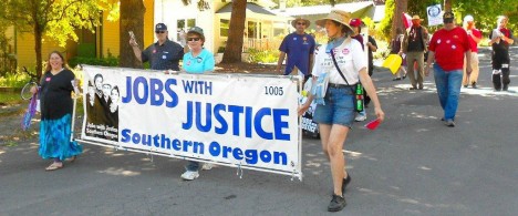 Adults walking on the street holding a large sign that says "Jobs with Justice Southern Oregon"