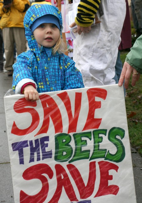 Child holds signs to save the bees