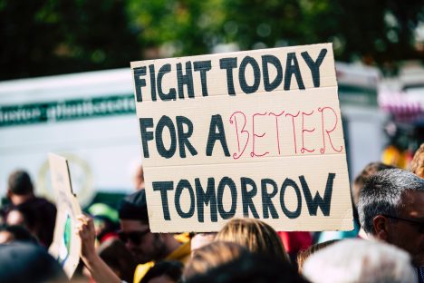 A cardboard sign above a crowd that reads Fight Today for a Better Tomorrow.