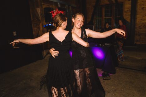 Two people in long black dresses dancing together.