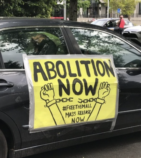 Protest sign taped to a car that reads: Abolition Now